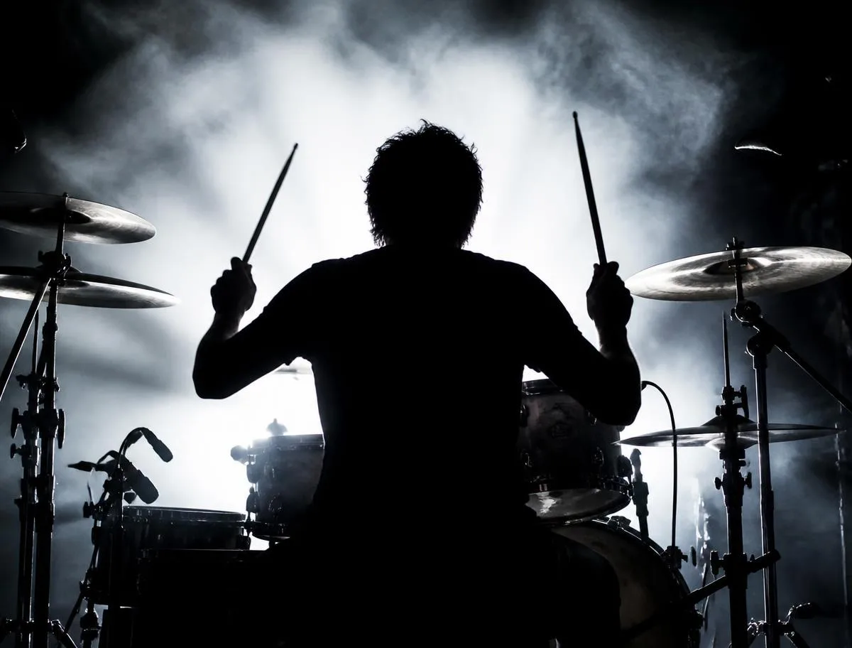 Drummer silhouette behind a kit in bright backlit smoke